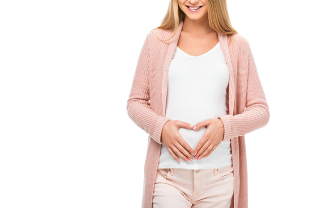vista cortada da mulher grávida mostrando sinal cardíaco com as mãos isoladas no branco
 - Foto, Imagem