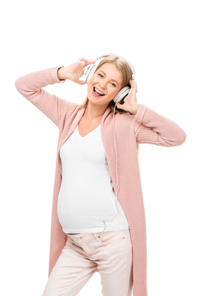 happy pregnant woman dancing with headphones isolated on white - Фото, изображение