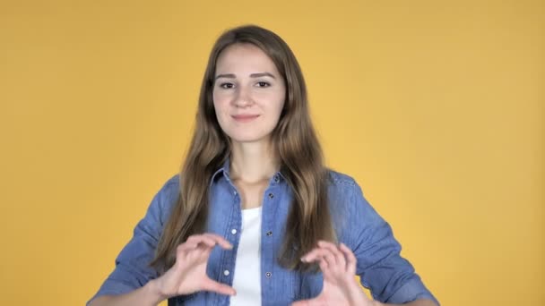 Handgemachtes Herz von hübscher Frau isoliert auf gelbem Hintergrund - Filmmaterial, Video
