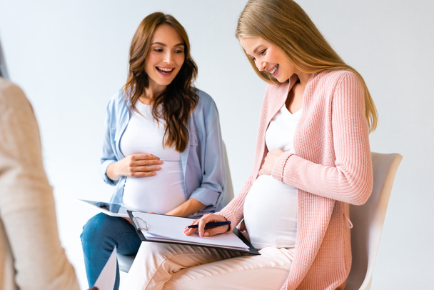 beautiful pregnant women talking on prenatal class isolated on grey - Foto, immagini