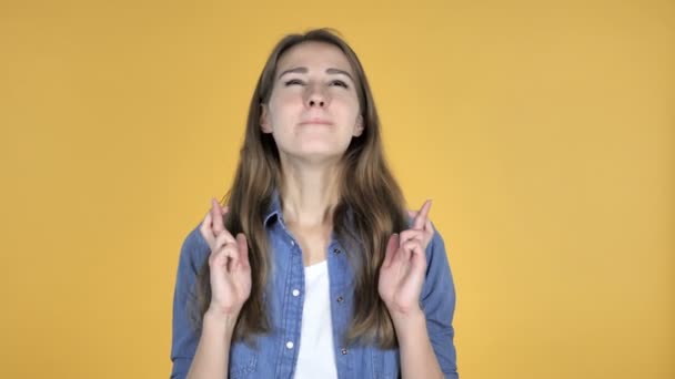 Mooie vrouw met vinger gekruist voor goed geluk op gele achtergrond bezorgd - Video