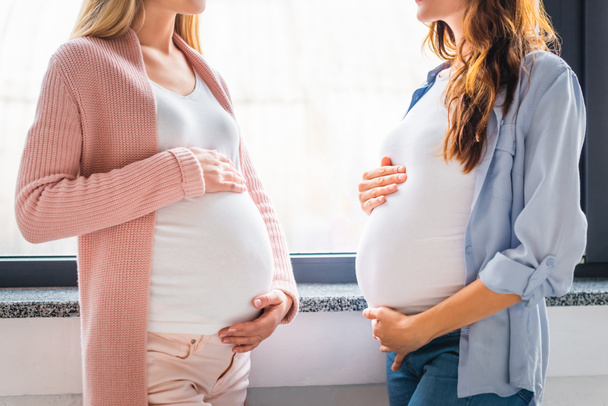 cropped view of smiling pregnant women standing by window - Photo, Image