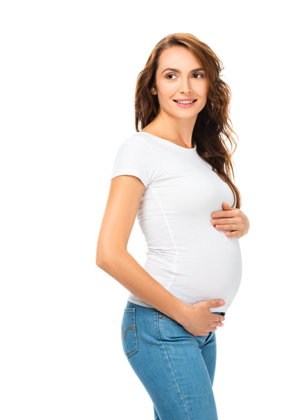 beautiful pregnant woman touching belly and looking away isolated on white - Foto, Imagen