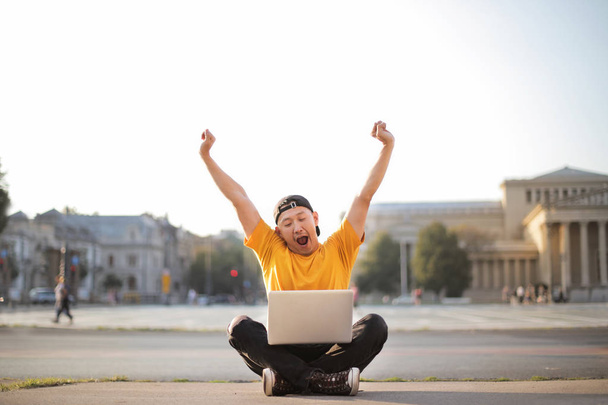 Ασιατικές νεαρός άνδρας με το laptop χαρούμενος στο δρόμο - Φωτογραφία, εικόνα