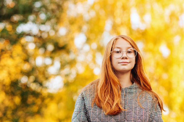 Retrato de cerca al aire libre de una hermosa niña preadolescente pelirroja con abrigo de cheques y anteojos
 - Foto, Imagen