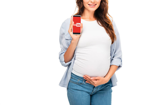 bijgesneden weergave van mooie zwangere vrouw houden smartphone met youtube app geïsoleerd op wit - Foto, afbeelding