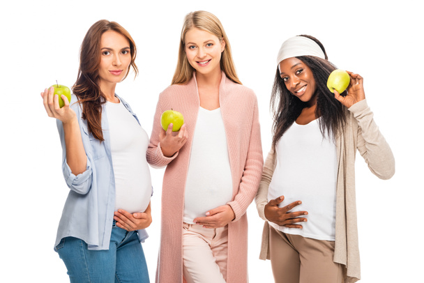 smiling pregnant women holding fruit in hands isolated on white - 写真・画像