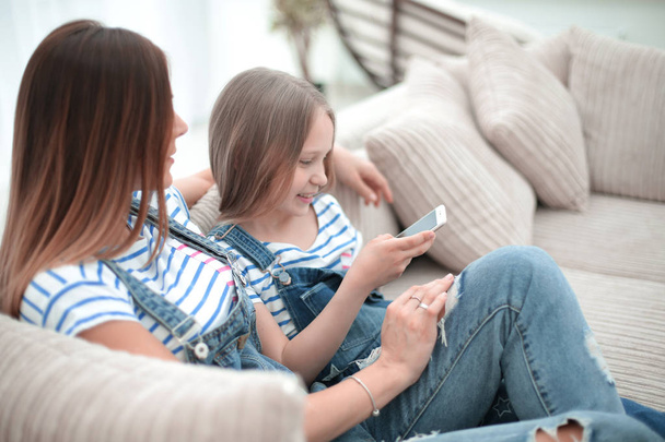 mom and her daughter reading SMS on smartphone - Foto, imagen