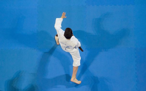 karate do kid against blue tatami background. Top View. Sport competition. - Photo, Image