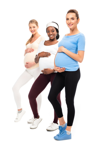 mujeres embarazadas sonrientes posando y cogidas de la mano en las barrigas aisladas en blanco
 - Foto, imagen