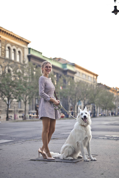 жінка вигулює свого собаку на вулиці
 - Фото, зображення