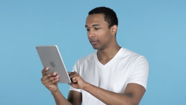 Losing Young African Man in Shock while Using Tablet Isolated on Blue Background - Footage, Video