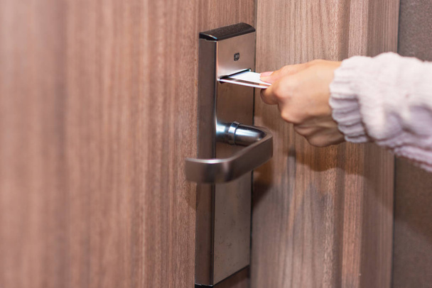 Tarjeta de inserción de mano mujer para abrir cerradura electrónica en la puerta del hotel
 - Foto, Imagen