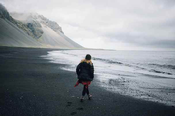 Jeune femme aventureuse sur la plage de sable noir
 - Photo, image