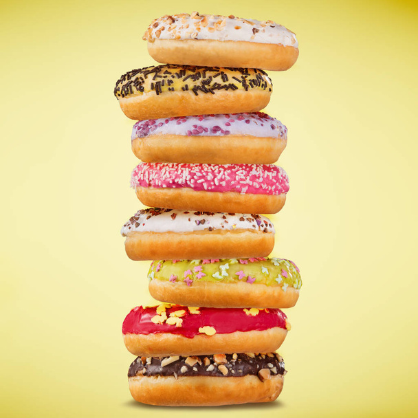 Stack of assorted donuts on pastel background. - Фото, зображення