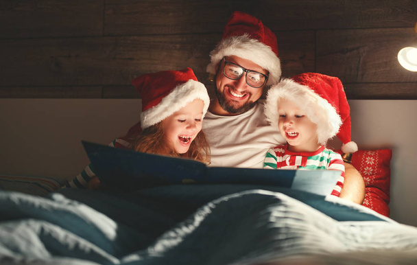 Wesołych Świąt Bożego Narodzenia! ojciec rodziny czyta dzieciom książkę przed snem w być - Zdjęcie, obraz