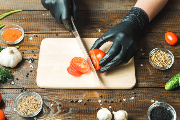 le mani delle donne tagliano un pomodoro, vicino a bugia la paprica, le erbe, i cetrioli e seasonings
 - Foto, immagini