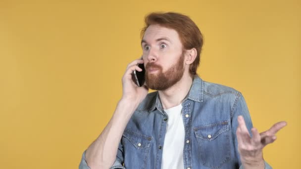Excited Redhead Man Talking on Phone Isolated on Yellow Background - Filmati, video