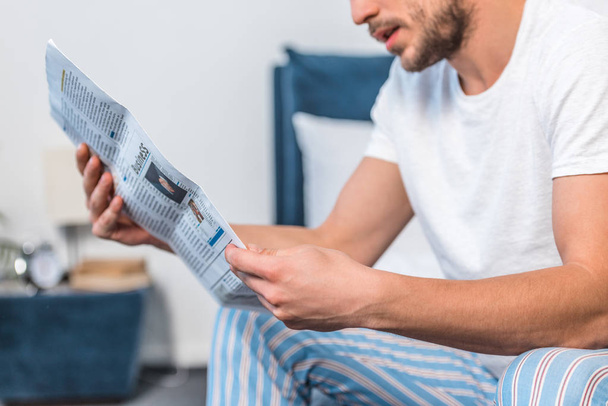 обрезанный образ человека, читающего газету в постели утром дома
 - Фото, изображение