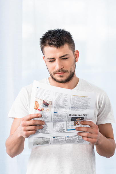 schöner Mann im Hemd liest morgens zu Hause Zeitung im Schlafzimmer - Foto, Bild