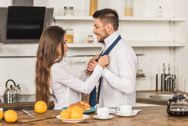дівчина зв'язує краватку хлопця вранці на кухні, концепція сексизму
 - Фото, зображення