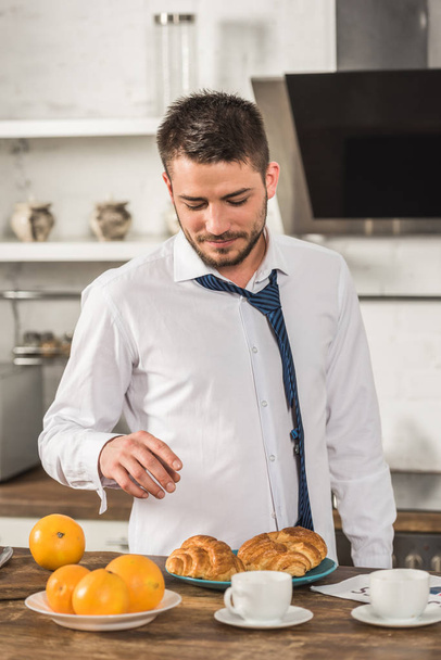handsome man taking croissant in morning at kitchen - Foto, Imagem