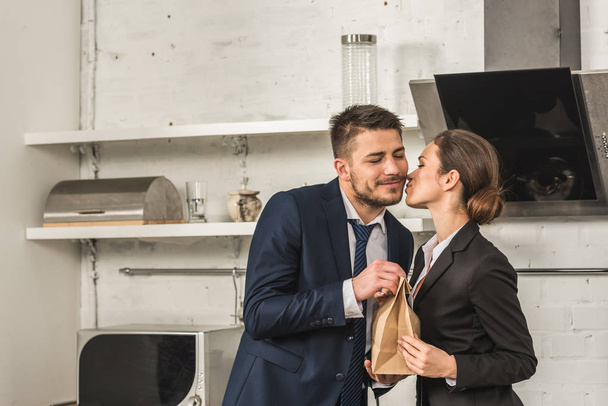 tyttöystävä antaa lounaan poikaystävä ja suudella häntä aamulla keittiössä, sosiaalisia rooleja käsite
 - Valokuva, kuva