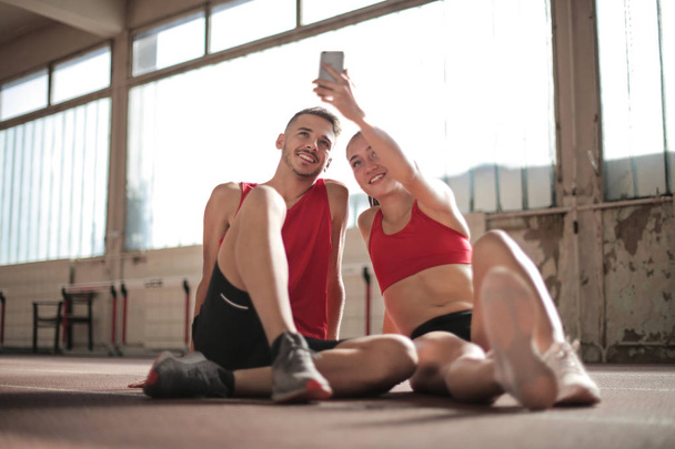 nuori urheilija nainen ja mies pitää taukoa harjoittelun aikana ja ottaa selfietä
 - Valokuva, kuva