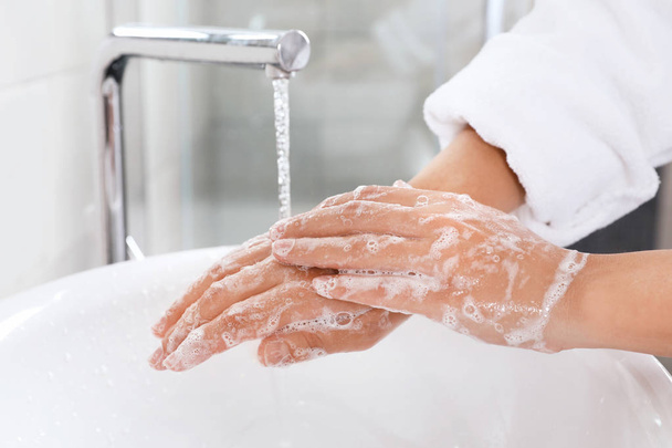 Woman washing hands with soap over sink in bathroom, closeup - Foto, immagini