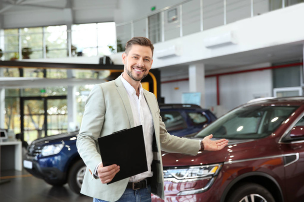 Salesman with clipboard in modern car dealership - Photo, image