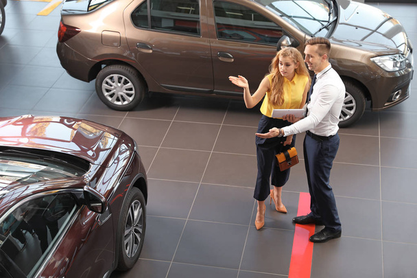 Young car salesman working with client in dealership - Foto, Imagem