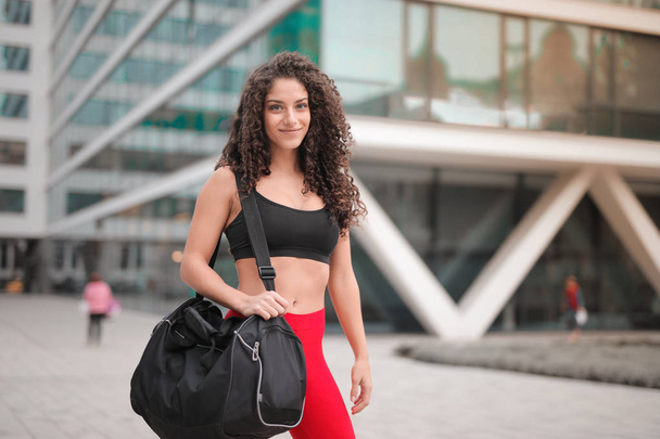 Young woman with sportbag in the street - 写真・画像