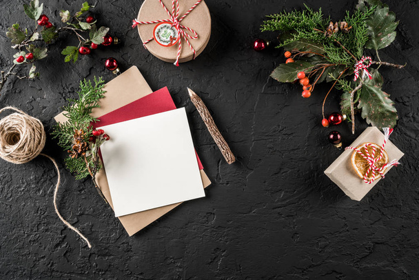 Vánoční dopis pro Santu na tmavém pozadí s tužkou, jedle větve, šišky, dárkové krabičky. Téma Vánoce a šťastný nový rok. Plochá ležel, horní pohled - Fotografie, Obrázek