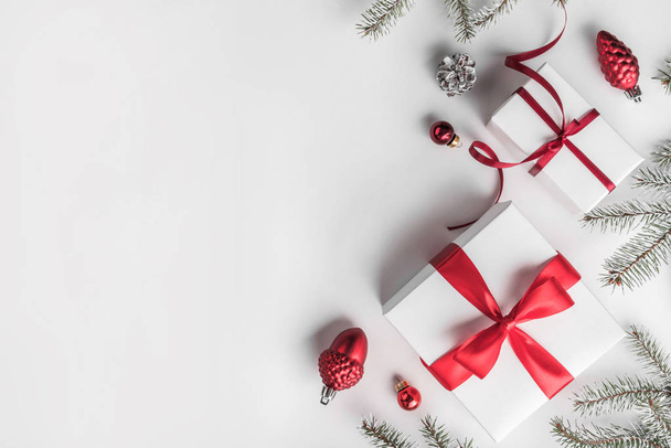 Confezioni regalo di Natale su sfondo bianco con rami di abete, pigne, decorazione rossa. Tema Natale e Felice Anno Nuovo. Layout piatto, vista dall'alto, spazio per il testo
 - Foto, immagini