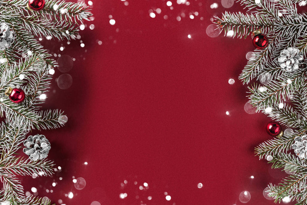 Creative layout frame made of Christmas fir branches, pine cones, gifts, red decoration on red background. Xmas and New Year theme, bokeh, glowing. Flat lay, top view - Φωτογραφία, εικόνα