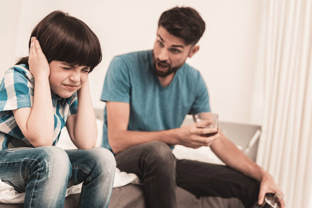 Little Boy Sitting in Room with Drunken Father. Crisis in Family. Alcoholism Problem Concept. Glass of Whiskey. Young Boy in Shirt. Modern Social Problems Concept. Sitting Sad Boy. - Foto, Imagen