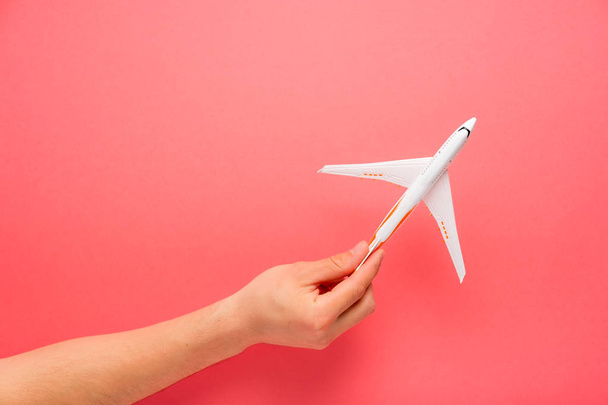 Hand carefully holding model plane. Airplane on pink color background. Security concept. - Fotó, kép