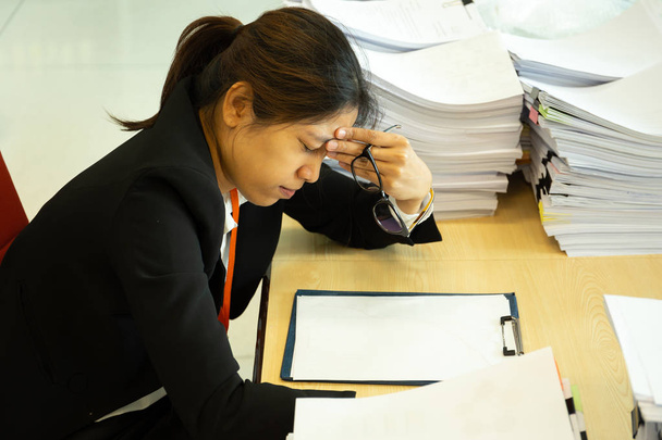 Empresaria descansando las manos en la cabeza con los ojos cerrados en el escritorio en la oficina
 - Foto, Imagen