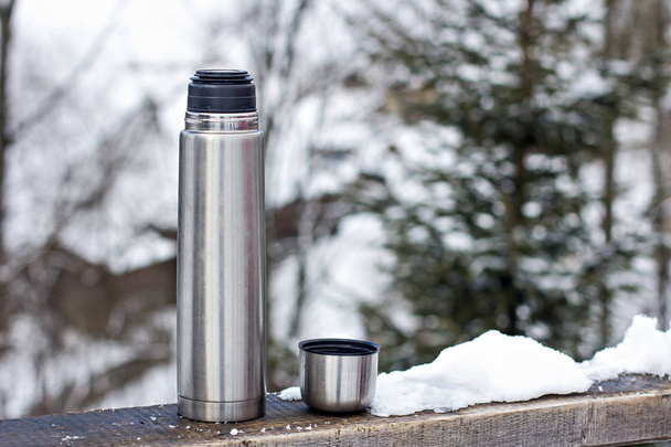 Thermos on the background of the winter landscape.  - Photo, Image