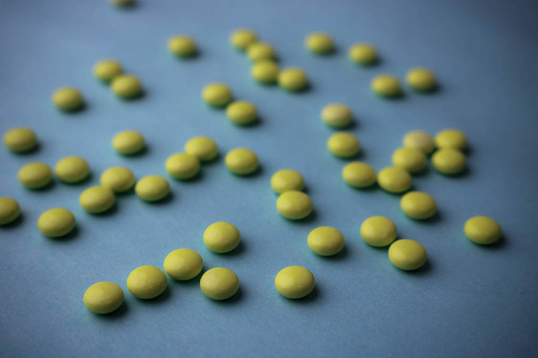 kleine gelbe orange schöne medizinische pharmazeutische runde Pillen, Vitamine, Medikamente, Antibiotika auf blauem Hintergrund, Textur. Konzept: Medizin, Gesundheitsfürsorge. flache Lage, Draufsicht - Foto, Bild