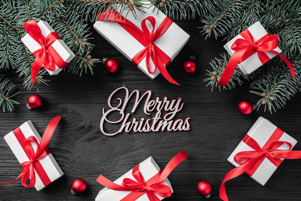 Χριστουγεννιάτικη κάρτα με λευκό δώρα και κλαδιά έλατου σε σκούρο φόντο ρουστίκ ξύλινα. Χριστούγεννα και Ευτυχισμένο το νέο έτος ευχετήρια κάρτα. Το Top view, επίπεδη lay.  - Φωτογραφία, εικόνα