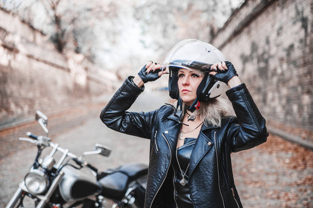 Prachtige biker vrouw poseren buiten met motorfiets.  - Foto, afbeelding