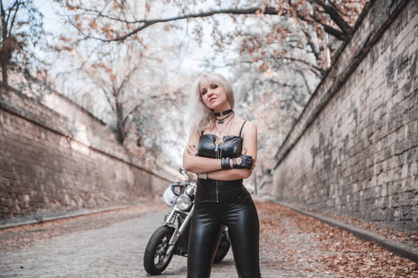 Beautiful biker woman posing outdoor with motorcycle.  - Fotografie, Obrázek