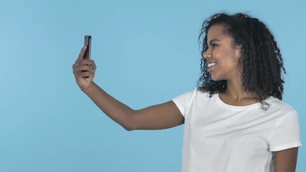 Chica africana tomando selfie con Smartphone aislado sobre fondo azul
 - Metraje, vídeo