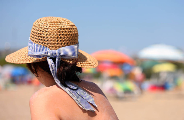 金持ちの女は、リゾートのビーチで麦わら帽子を太陽の下で彼女自身を日焼け - 写真・画像