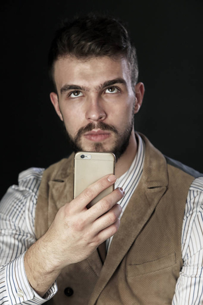 closeup portrait of the beautiful charismatic young man with a beard, a mobile phone in hand  - Foto, Bild