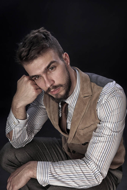 closeup portrait of the beautiful charismatic young man with a beard wearing pants, shirt, vest and tie on a dark background studio - Photo, image