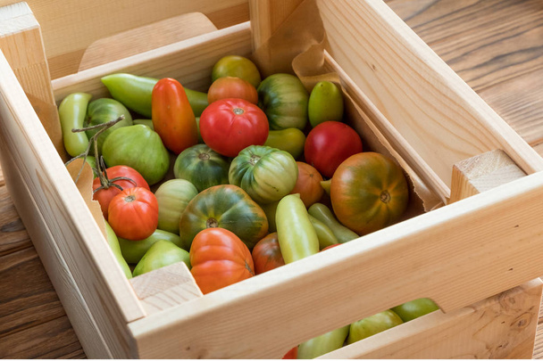 Κόκκινες και πράσινες ντομάτες σε ένα ξύλινο υπόβαθρο. Συγκομιδή ντομάτας - Φωτογραφία, εικόνα