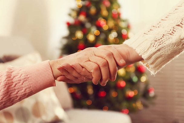 高齢者女性の背景に装飾された休日の松の木と自宅でクリスマスを祝います。特別養護老人ホーム老婦人。クローズ アップ、ショットをトリミング領域をコピー. - 写真・画像