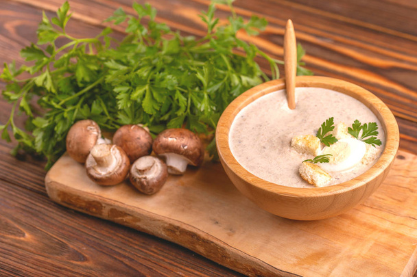 Tasty pureed mushroom soup in wooden bowl with ingredients. Healthy food concept. Rustic wooden background. Horizontal view. Copy space - Foto, Imagem